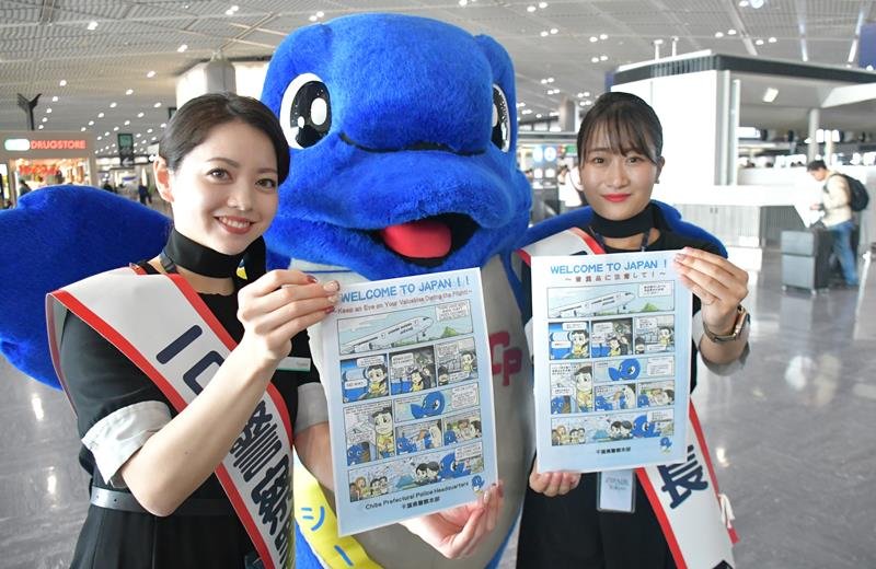 航空機内での窃盗被害防止に向けた注意喚起の漫画を紹介する一日警察署長の客室乗務員ら＝２２日、成田市の成田空港