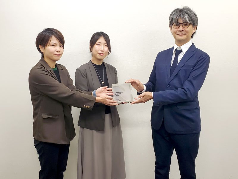 ＬＩＮＥの担当者（右）からトロフィーを授与される千葉日報の編集担当者＝千葉市中央区の千葉日報社