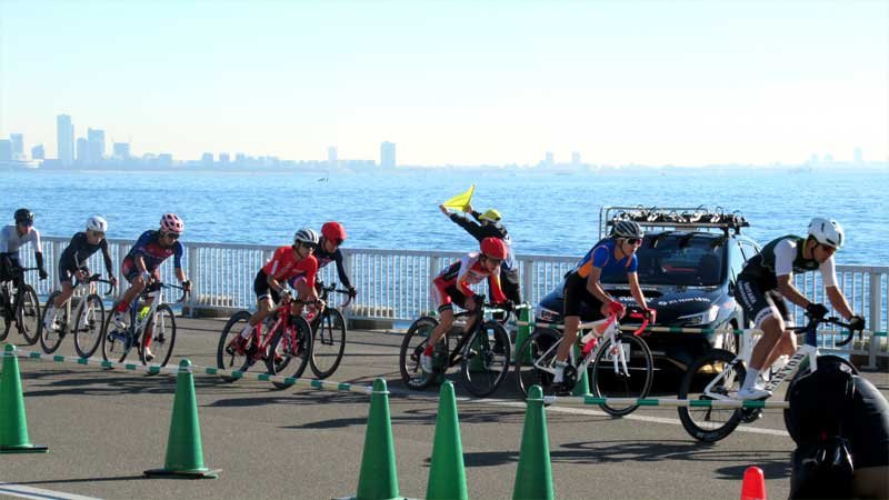 東京湾を背景にコースを疾走する選手たち＝３０日、浦安市