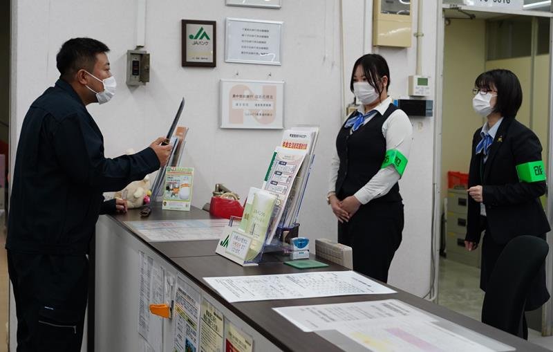 窓口で刃物を取り出し脅す強盗役（左）と落ち着いて対応する職員＝匝瑳市
