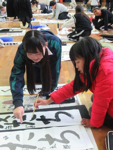 信篤小で行われた「書き初め」の練習で児童を指導する書道部員＝市川市
