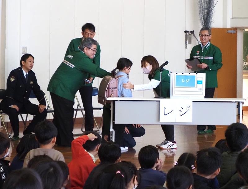 不審者役から逃れ、模擬コンビニに駆け込む訓練。助けを求める児童代表（中央）に店員が対応した＝富津市
