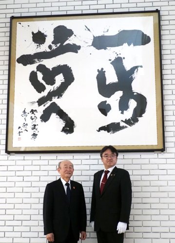 ロビーに展示された「一歩前へ」の前に立つ辻元さん（左）と粕谷市長＝袖ケ浦市