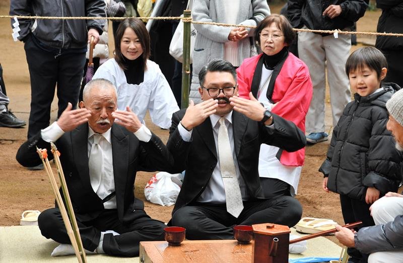 ひげをなでるしぐさをして酒を勧める旧当番の氏子＝１２日、香取市の側高神社
