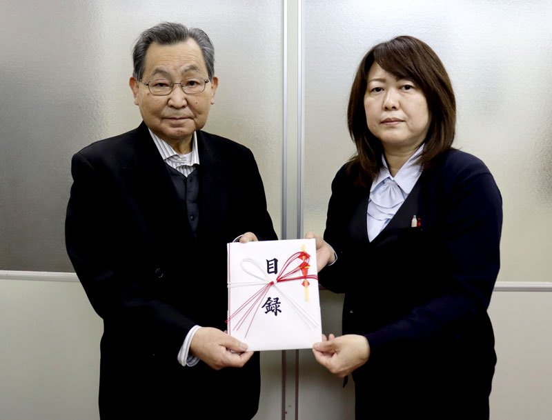 寄付目録を手にする高品ハウジングの山中操代表取締役（左）と秘書の石川まゆみさん