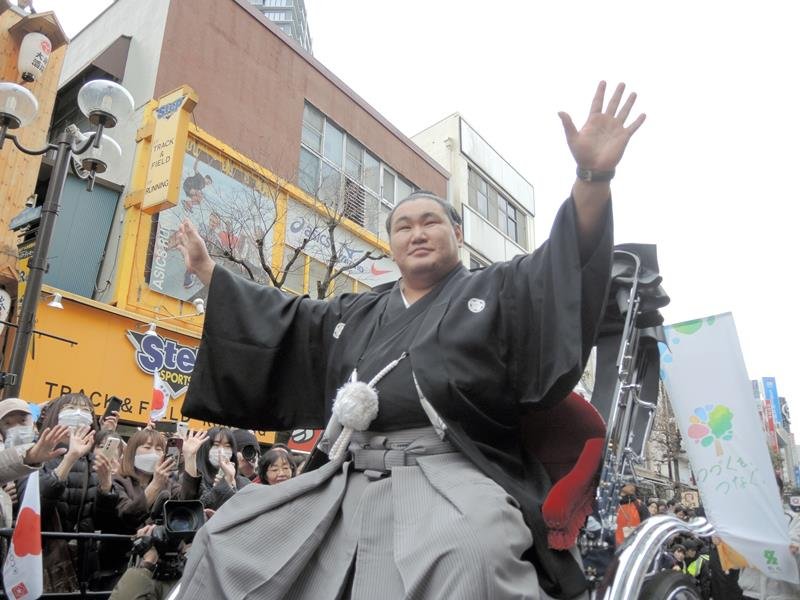 柏駅東口での祝賀パレードで祝福に手を上げ応える豊昇龍関＝１６日、柏市