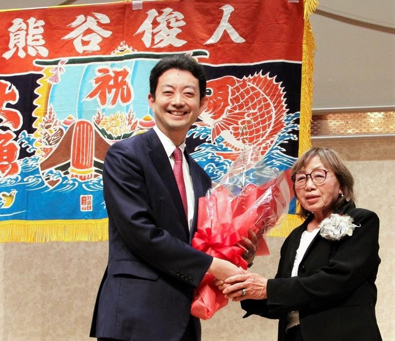 後援会の女性から花束を受け取り、笑顔を見せる熊谷氏＝１６日、千葉市中央区