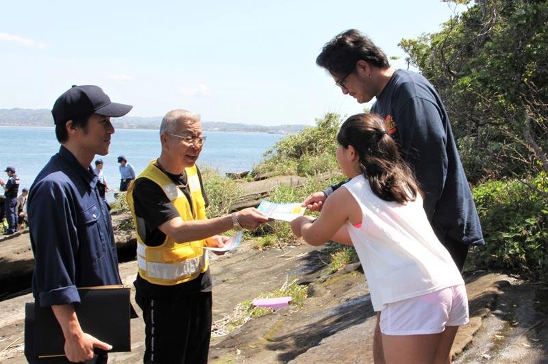 リーフレットを受け取る観光客ら＝３日、館山市の沖ノ島
