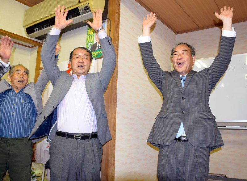 初当選を決め万歳する緑川氏（右）と選対委員長を務めた前町長の林氏（右から２人目）ら＝２５日午後１０時５分ごろ、白子町古所の事務所