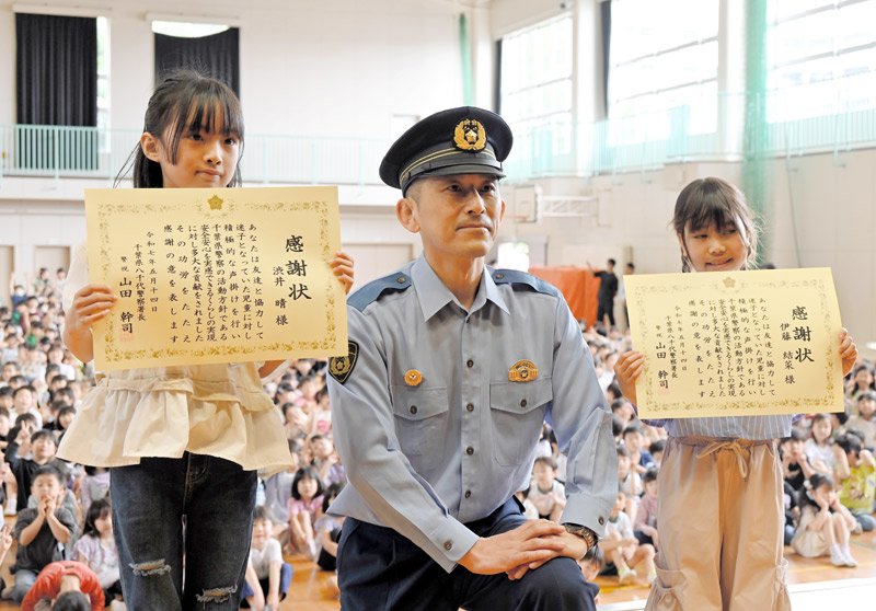 迷子の女の子を助け、全校児童の前で感謝状を受け取った渋井さん（左）と伊藤さん（右）＝１４日、八千代市緑が丘の市立新木戸小学校
