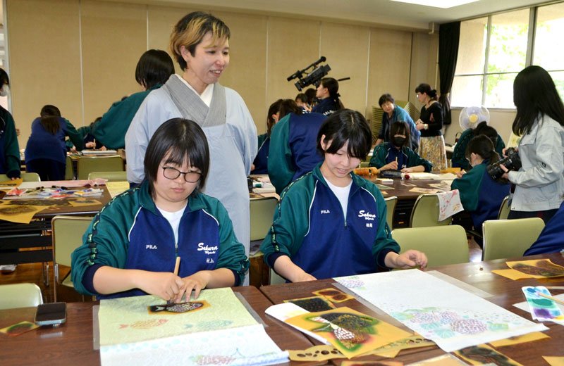 桑原さん（中央）から教わりながら、筆で色をのせ友禅染に挑戦する高校生＝佐倉市の県立佐倉東高
