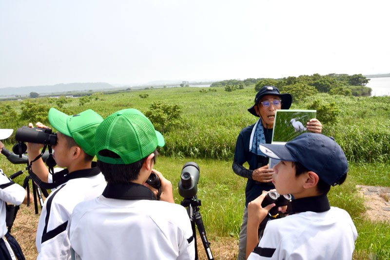 希少な鳥も生息する利根川下流域のヨシ原で子どもたちに説明する柳堀会長＝香取市