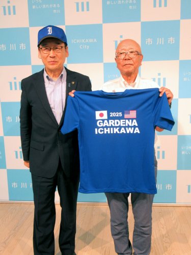 米ガーデナ市で行われる少年野球親善試合のためのＴシャツを披露する中村さん（右）。左は田中市長＝市川市役所
