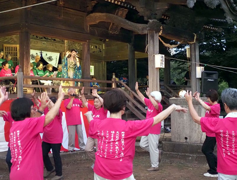 復活した「野里音頭」のお披露目。社殿上で峰丘奈知さんが歌い、住民の踊りの輪ができた＝袖ケ浦市