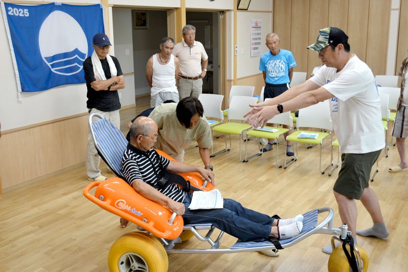 水陸両用のモビチェアについて説明する榊原さん（右）＝勝浦市
