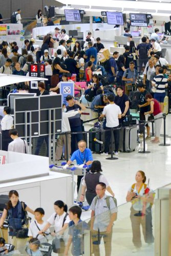 成田空港で８日、お盆の長期休暇を海外で過ごす人らの出国ラッシュが始まった。国際線のカウンターでは、搭乗手続きのために多くの旅客が列を作った