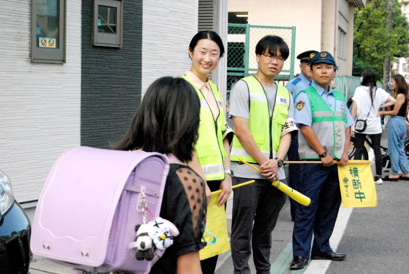 登校中の児童とあいさつを交わす留学生ら＝１日午前８時ごろ、千葉市中央区祐光の院内小学校前