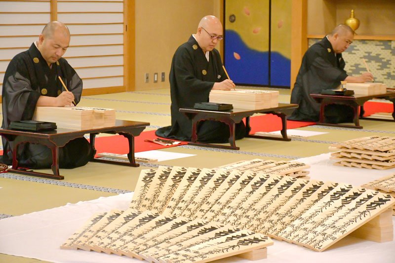 平安の願いを込めて正月用の護摩札を浄書する成田山新勝寺の僧侶＝１２日、成田市