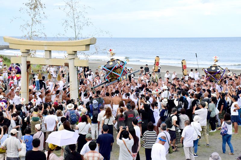 釣ケ崎海岸の鳥居の前で神輿を掲げる担ぎ手ら＝１３日、一宮町