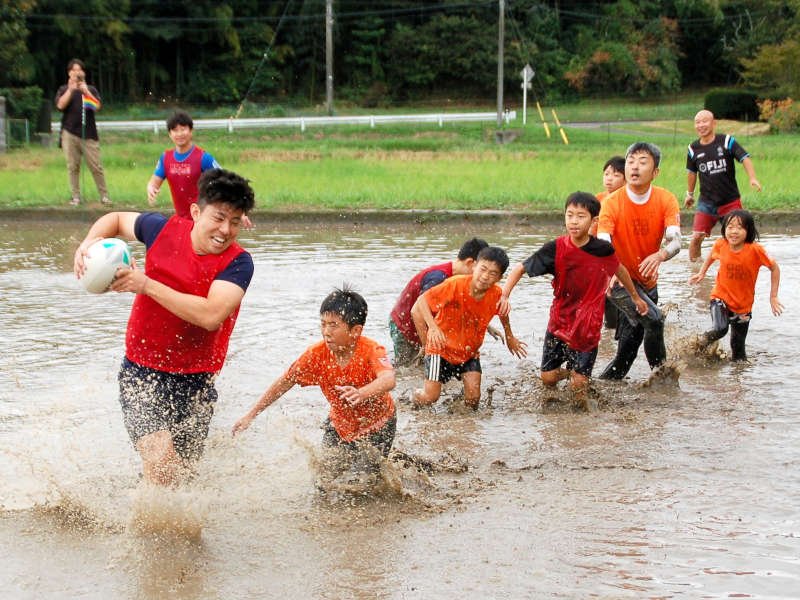 泥水をはね上げながら競り合う選手＝２７日、市原市