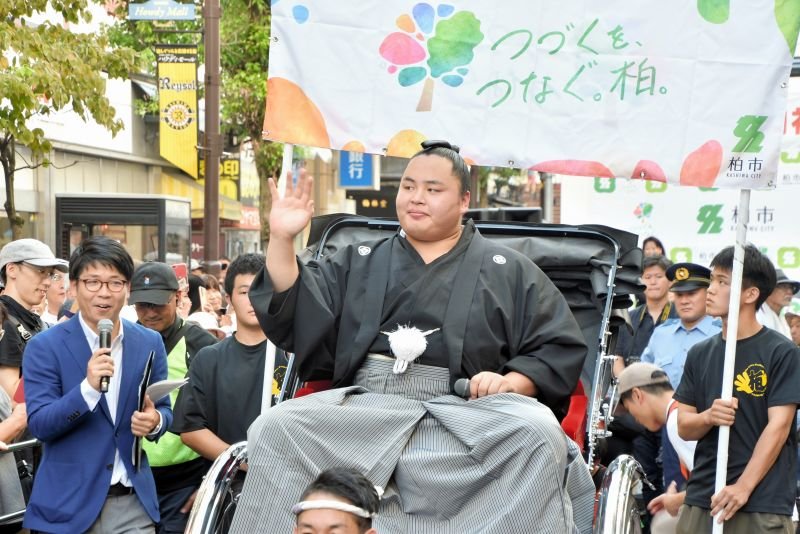祝賀パレードで沿道の声援に応えるように手を振る琴勝峰関＝７日、柏市