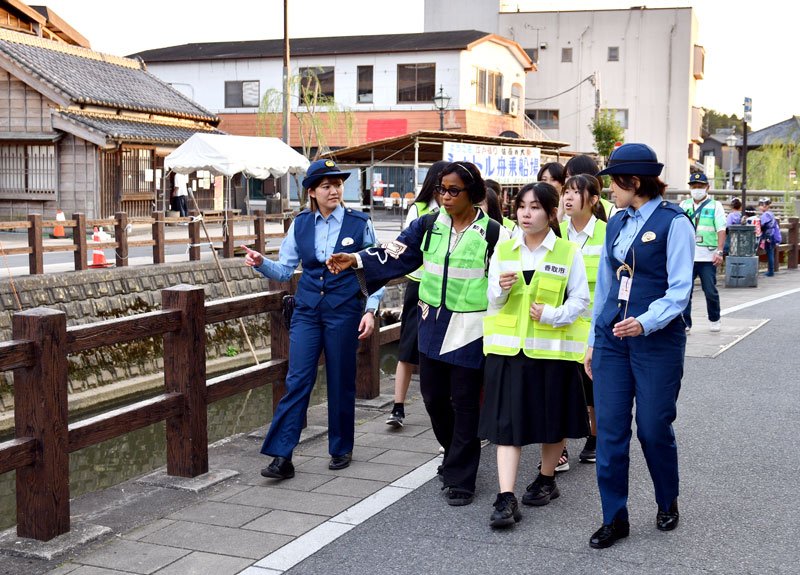 佐原の大祭の会場で香取署員と防犯パトロールを行う高校生と留学生＝１０日、香取市