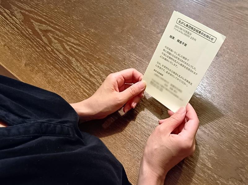 乳がん検診で届いた「精査不要」の通知を見つめるちひろさん（仮名）。翌年、超音波検査で乳がんが見つかった＝千葉県内
