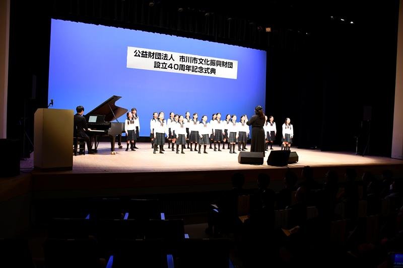 記念式典で合唱を披露する国府台女子学院小学部の児童ら＝市川市文化会館
