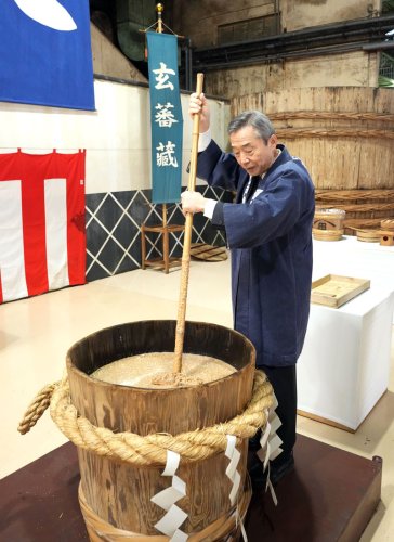 しょうゆの原材料が入った木おけをかき混ぜるヒゲタ醤油の浜田社長＝２１日、銚子市