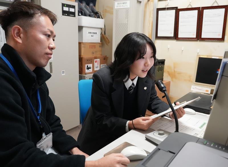 電話de詐欺注意喚起放送の練習をする鈴木さん（右）＝銚子市役所
