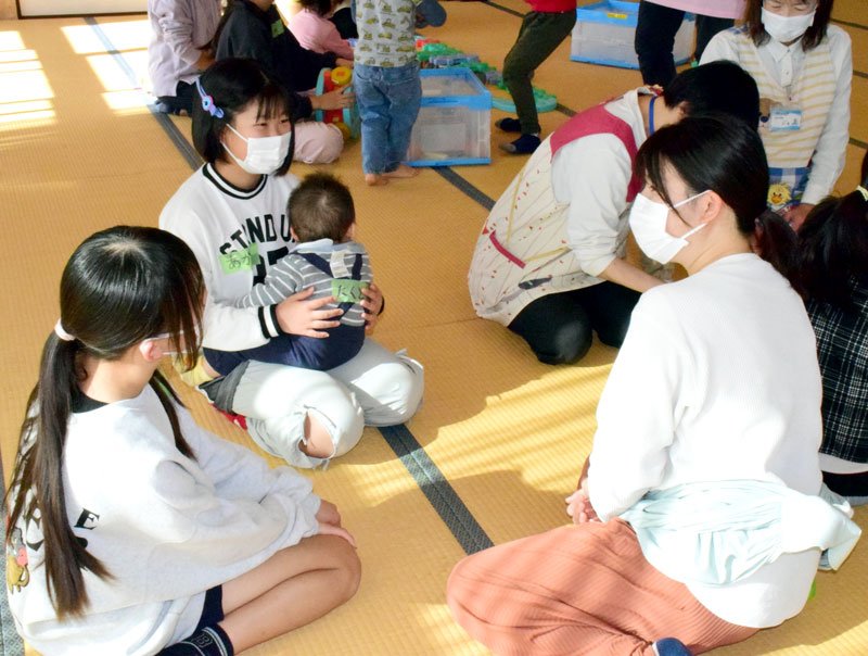 赤ちゃんを抱っこして母親の体験談を聞く児童ら＝長生村