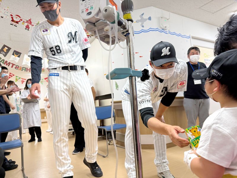 病院を訪れて子どもたちと交流し、お菓子をプレゼントする千葉ロッテの唐川投手（中央右）＝３日、成田市内（球団提供）