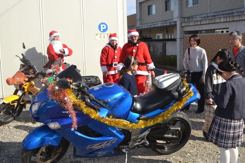 サンタ姿のライダーがバイクで児童養護施設を訪れプレゼントを渡した＝酒々井町
