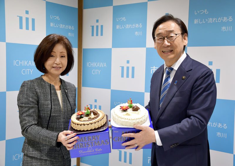 寄贈したクリスマスケーキを手にする横山社長（左）。右は田中市長＝２３日、市川市役所