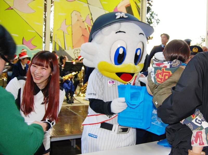 来場者に反射材キーホルダーや啓発チラシが入ったバッグを手渡す（左から）ＭＩＫＵさんとマーくん＝１８日、千葉市美浜区のイオンモール幕張新都心