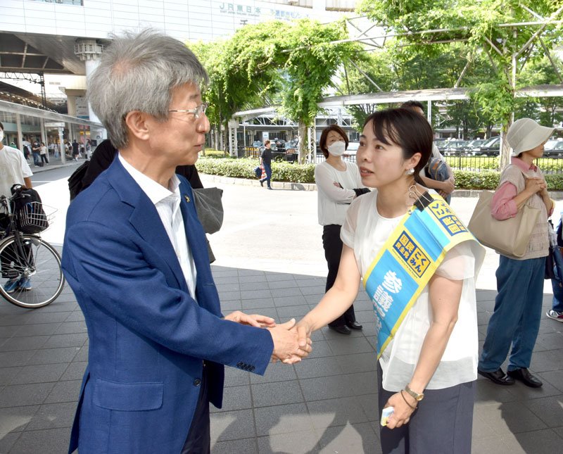 ７月３日の参院選公示を前にした国民の街頭演説会に聴衆の一人として姿を見せた石井氏（左）。演説会後に小林氏と握手で健闘を誓い合った＝６月３０日、千葉市中央区のＪＲ千葉駅前