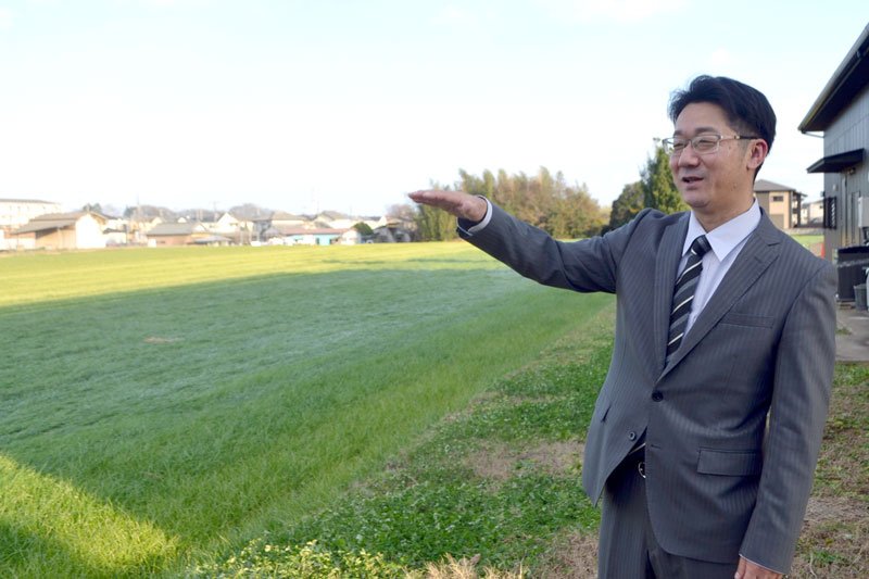 「創業当時から栽培方法にこだわってきている」と話す増田社長。左側は生牧草が育つ農場＝四街道市の中央牧草センター