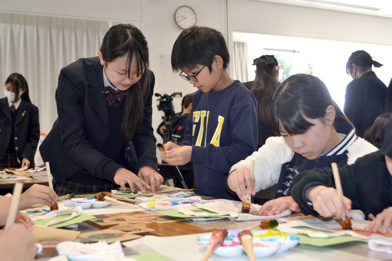佐倉東高校生（左）のアドバイスを受けながら真剣な表情で友禅染に挑戦する小学生＝佐倉市の夢咲くら館