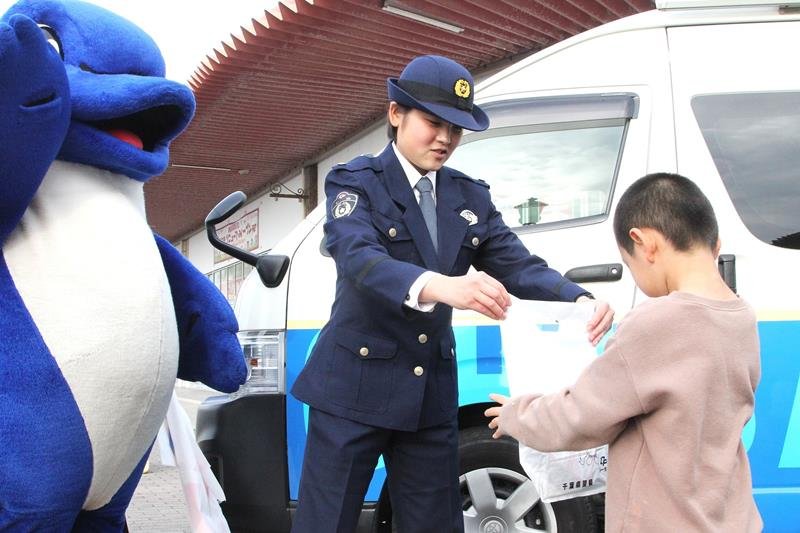 啓発グッズを子どもに配る四本巡査＝館山市

