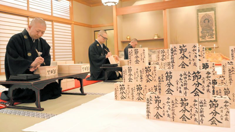 成田山新勝寺で節分に向けた福枡（ます）作りが行われ、僧侶らが人々の幸せを願いながら、１年間の日数と同じ３６５個の枡に丁寧に筆を走らせた＝１３日、成田市