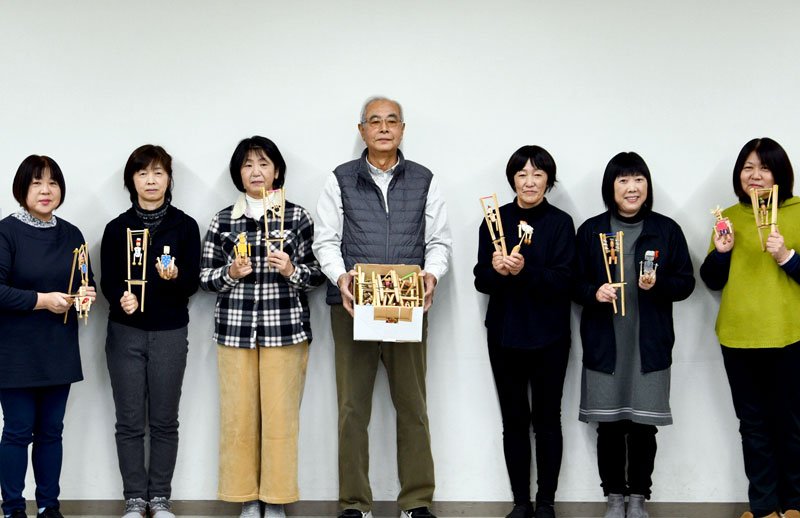 手作りの木製人形のおもちゃを香取市に寄贈した菅谷さん（中央）＝香取市役所

