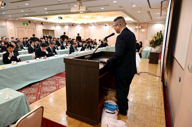 講演をする「盲導犬を普及させる会」の松井会長（右）。足元に盲導犬が寄り添った＝２０日、千葉市美浜区