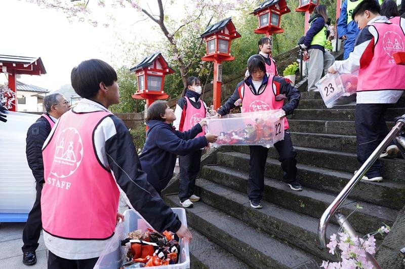 遠見岬神社の石段への飾り付けで、大人と協力して作業を進める運動着姿の勝浦中の生徒＝２１日、勝浦市


