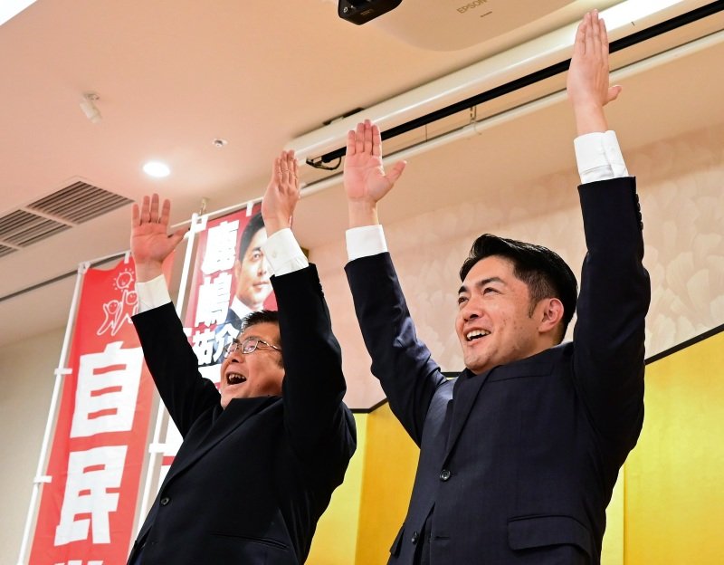 万歳をする自民党の鹿嶋氏（右）＝８日、船橋市
