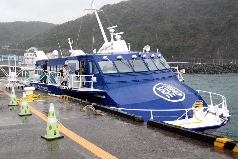 港を出るジェット船「セブンアイランド結（ゆい）」に乗船する乗客ら＝２月２５日、東京都大島町岡田の岡田港