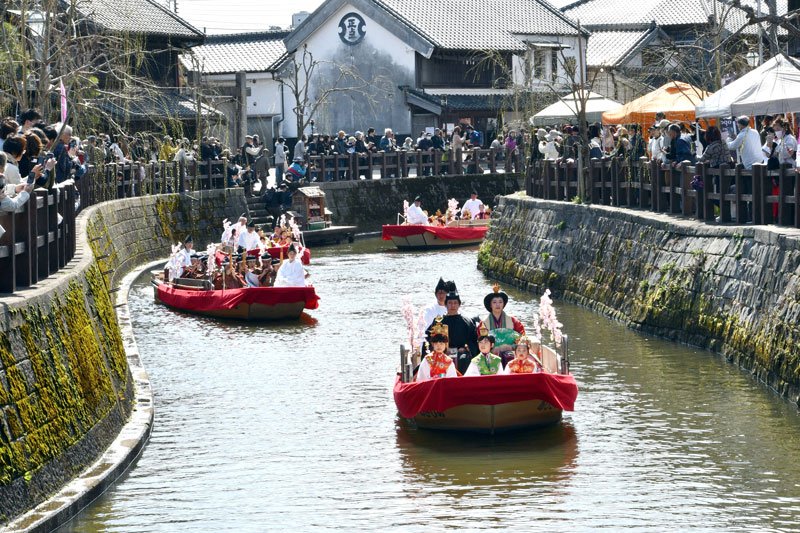 春の陽気の中、ひな人形の衣装をまとった参加者が舟で佐原の町並みを巡った＝７日、香取市