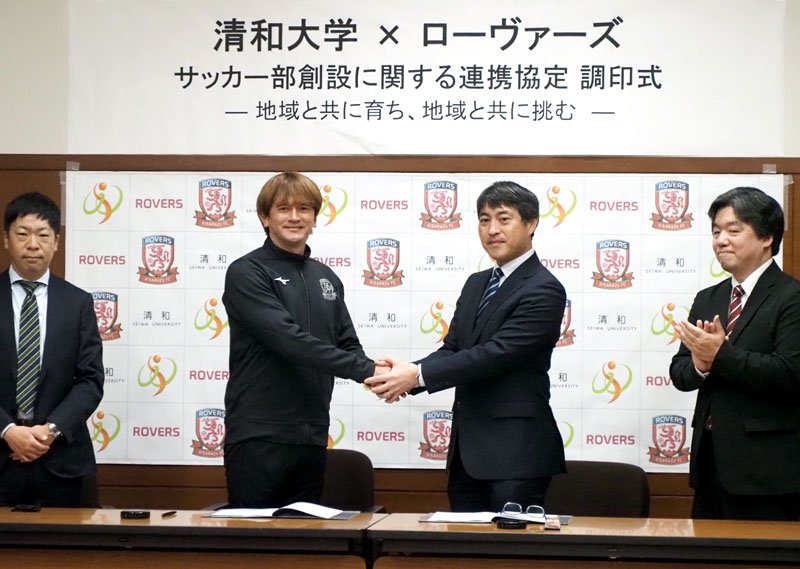 サッカー部創設に向けて握手をするカレンさん（左）と真板理事長＝木更津市
