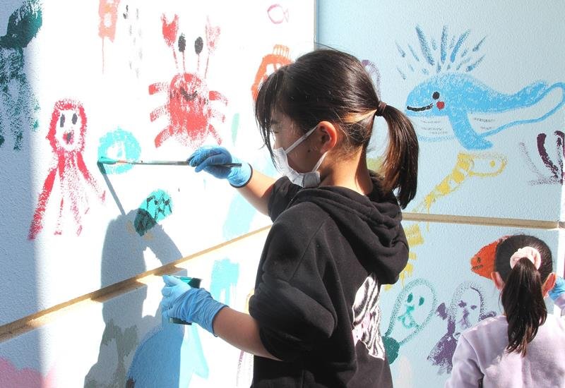 船形小学校体育館の壁に絵を描く女児＝館山市
