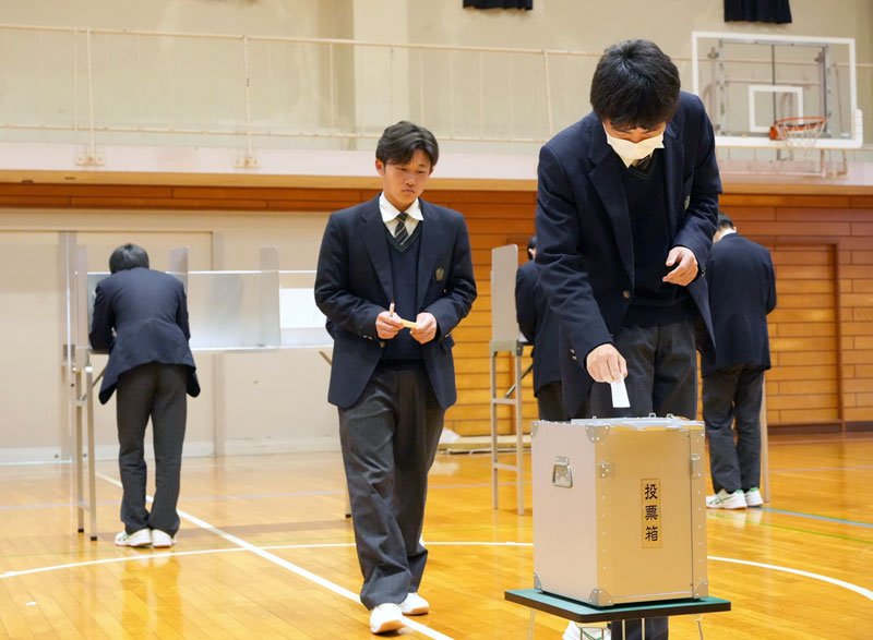 実際の選挙で使用される投票箱へ投票用紙を投じる東総工高２年生＝１９日、旭市