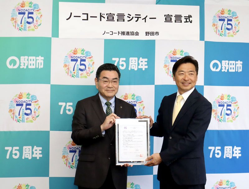 「ノーコード宣言シティー」の宣言書を掲げる鈴木市長（左）と中山代表理事（野田市提供）